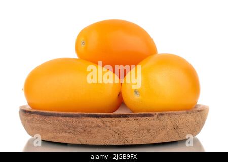 Three ripe yellow tomatoes on a wooden tray, close-up, isolated on a white background. Stock Photo