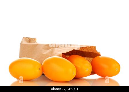 Several ripe yellow tomatoes with a paper bag, close-up, isolated on a white background. Stock Photo