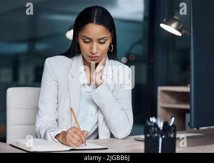 I should make a note of checking on my investments. an attractive young businesswoman sitting in her office at night and looking contemplative while Stock Photo