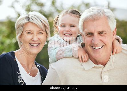 The only thing better than being a parent is being a grandparent. a senior couple spending time outdoors with their granddaughter. Stock Photo