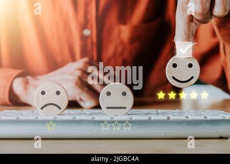 Businessman hand holding smiley face emoticon on virtual touch screen.good feedback rating and positive customer review, experience, satisfaction surv Stock Photo