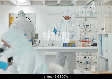 Conducting experiments under defined conditions. a scientist wearing a radiation suit while working with samples in a lab. Stock Photo