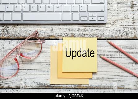 PC keyboard, glasses, pencils and note paper with word UPDATE on light wooden background Stock Photo
