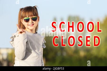 Text SCHOOL CLOSED and cute little girl with sunglasses outdoors Stock Photo