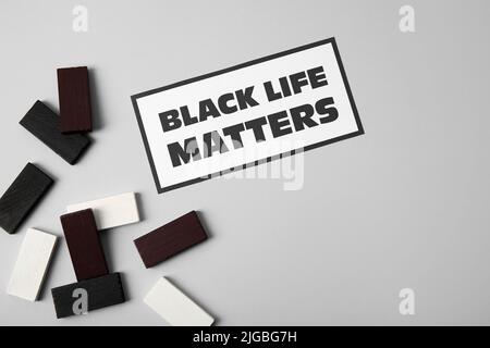 Black, white blocks and paper sheet with text BLACK LIFE MATTERS on grey background Stock Photo
