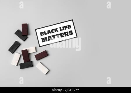 Black, white blocks and paper sheet with text BLACK LIFE MATTERS on grey background Stock Photo