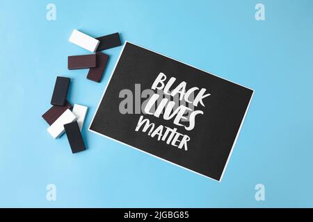 Black, white blocks and paper sheet with text BLACK LIFE MATTERS on color background Stock Photo