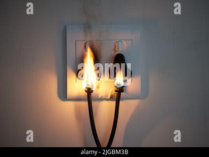 I hope youve got insurance. two plugs in a wall socket catching fire. Stock Photo