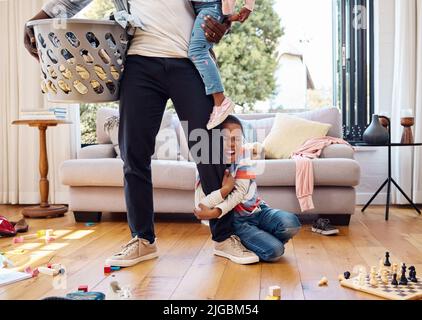When youre having a bad day, just scream. a little boy throwing a tantrum while holding his parents leg at home. Stock Photo