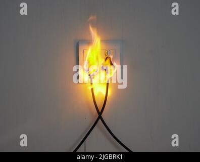 What a disaster. two plugs in a wall socket catching fire. Stock Photo