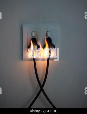 Are you covered. two plugs in a wall socket catching fire. Stock Photo
