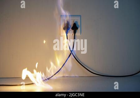 Mistakes happy. two plugs in a wall socket catching fire. Stock Photo