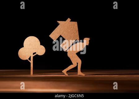 Representation in cut cardboard of a man carrying a house on his back. Rising house prices, high mortgages and difficulty in paying rent Stock Photo