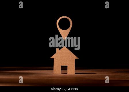 Cardboard cut-out representation of a little house with the position symbol on the map. Concept of having as a destination the acquisition of a house Stock Photo