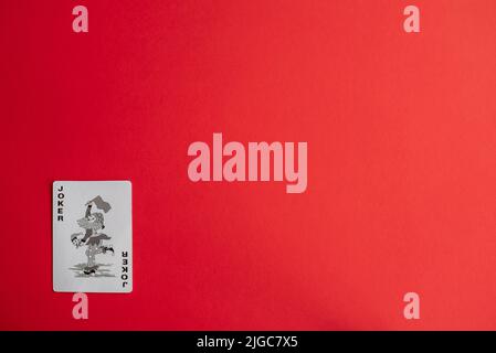 A Joker playing card against red background Stock Photo