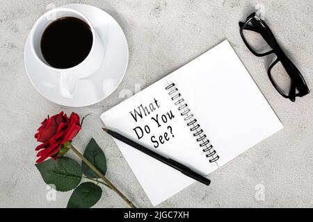 What to you see text on note book on white marble table with coffee, reading glasses, pen and roses. Stock Photo