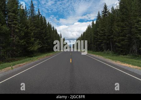 Long empty road in the mountain forest stretching into horizon, Central Oregon Cascade Lakes Scenic Highway Stock Photo