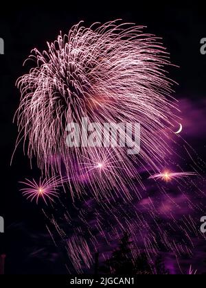 Montreal, Canada - June 25 2022: Fire works show with quarter moon in background at La Ronde in Montreal Stock Photo