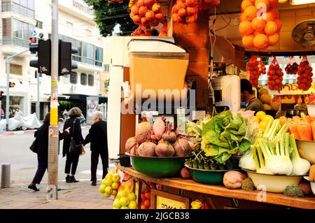 TEL AVIV, ISRAEL - DECEMBER 28, 2017: Urban scene. Fresh detox drink at juice stall. Old ladies cross street and young beautiful woman seen at billboa Stock Photo