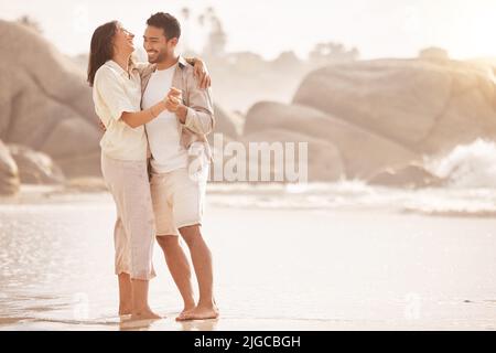 Take my hand and well dance into the sunset. a young couple dancing on the beach. Stock Photo