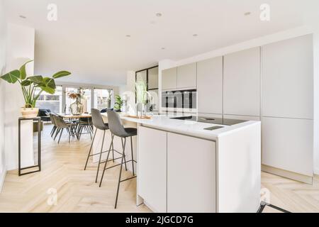 Modern cabinetry with appliances located in a bright open plan kitchen next to the dining room in a stylish apartment Stock Photo