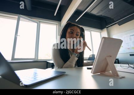 Concentrated office worker putting on makeup before cosmetic mirror Stock Photo