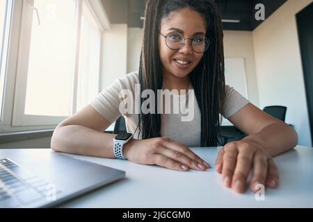 Joyous female office worker posing for camera at desk Stock Photo