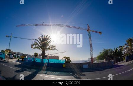 February 03 2022-Mountain top construction site in the Canary Island resort town of Puerto Rico with blue skies and a very tall crane Stock Photo