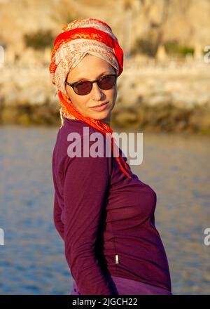 Mature woman poses in Puerto Rico Canary with orange turban sunglasses and burgundy clothes Stock Photo