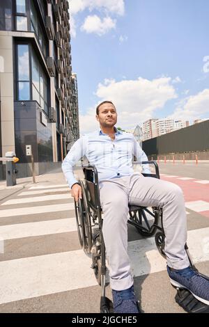 Disabled man seated in wheelchair crossing crosswalk Stock Photo