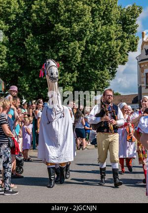 Straznice, Czech Republic - June 25, 2022 International Folklore Festival. People in folk costumes in a procession with a horse mask Stock Photo