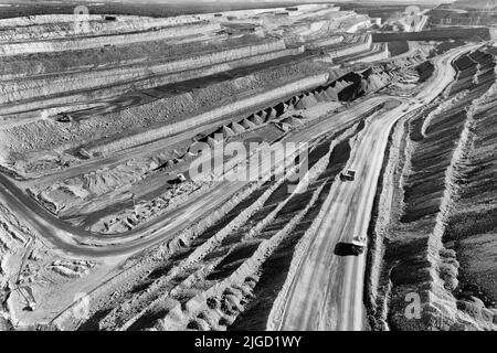 Deep excavated open pit black coal iron ore mine in NSW of Australia Hunter valley - aerial view of trucks and excavators. Stock Photo