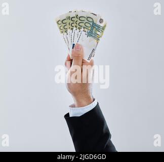 Power doesnt corrupt people, people corrupt power. a businessman stretching out his hand holding money against a grey background. Stock Photo