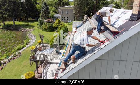Roofers retiling the roof of a home in Athens, Greene County, New York, USA Stock Photo