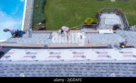Roofers retiling the roof of a home in Athens, Greene County, New York, USA Stock Photo