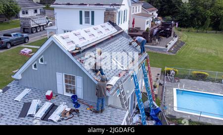 Roofers retiling the roof of a home in Athens, Greene County, New York, USA Stock Photo