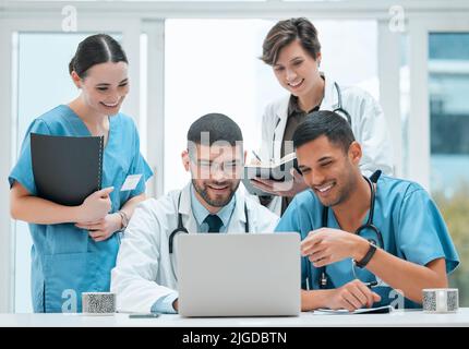 Using technology to improve the medical field. a group of doctors using a laptop together at work. Stock Photo