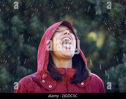 Without rain, there wont be rainbows. a young woman sticking out her tongue to feel the rain outside. Stock Photo