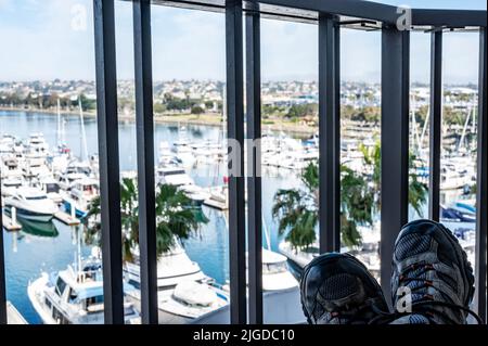 Shoes resting on a table with a balcony view of the bay harbor in San Diego California with docked boats  Stock Photo