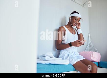 Live in peace with yourself. a young woman listening to music in a locker room. Stock Photo