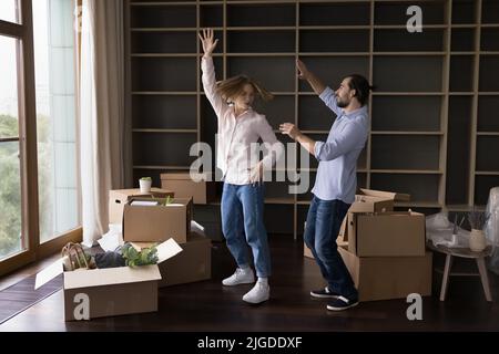 Excited young couple enjoying moving party, dancing to music Stock Photo