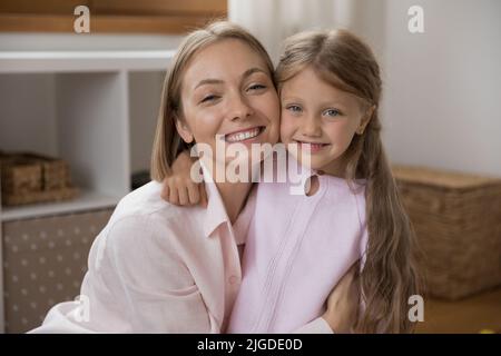 Happy young mother and little daughter hugging with cheek touches Stock Photo