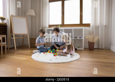 Young caring loving dad entertaining two little sibling kids Stock Photo