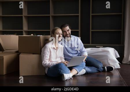 Happy couple using laptop, consulting internet for interior design samples Stock Photo