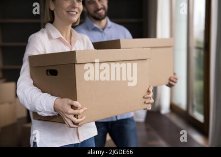 Happy smiling young couple holding moving cardboard boxes cropped shot Stock Photo