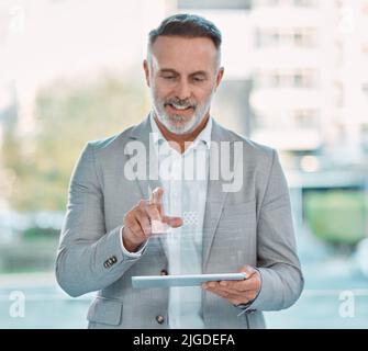 Do not allow people to dim your shine. an mature businessman sitting alone and using a tablet with graphical images in a office. Stock Photo