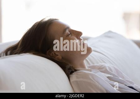 Serene smiling young woman relax on cozy sofa, close up Stock Photo