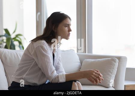 Sad disappointed teen girl sits thinking staring into distance Stock Photo