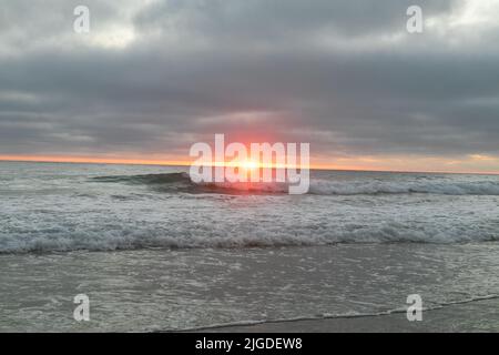 July 10, 2022, San Diego, CA, United States: The cilffs, trees, rocks, beach, waves, orange clouds, and ocean during the glimmering summer sunset in La Jolla, California on Saturday, July 9th, 2022  (Credit Image: © Rishi Deka/ZUMA Press Wire) Stock Photo