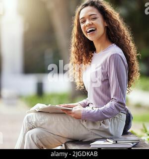Student life is treating me well. a young female student studying in nature. Stock Photo